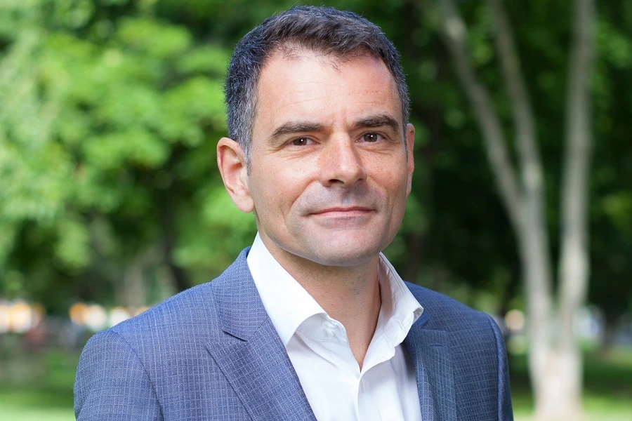 man in grey suit with trees in background